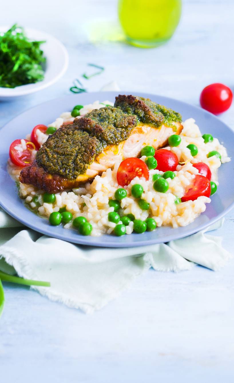gebackenes Lachsfilet mit Bärlauch-Kräuterkruste angerichtet auf Gemüserisotto auf einem Teller
