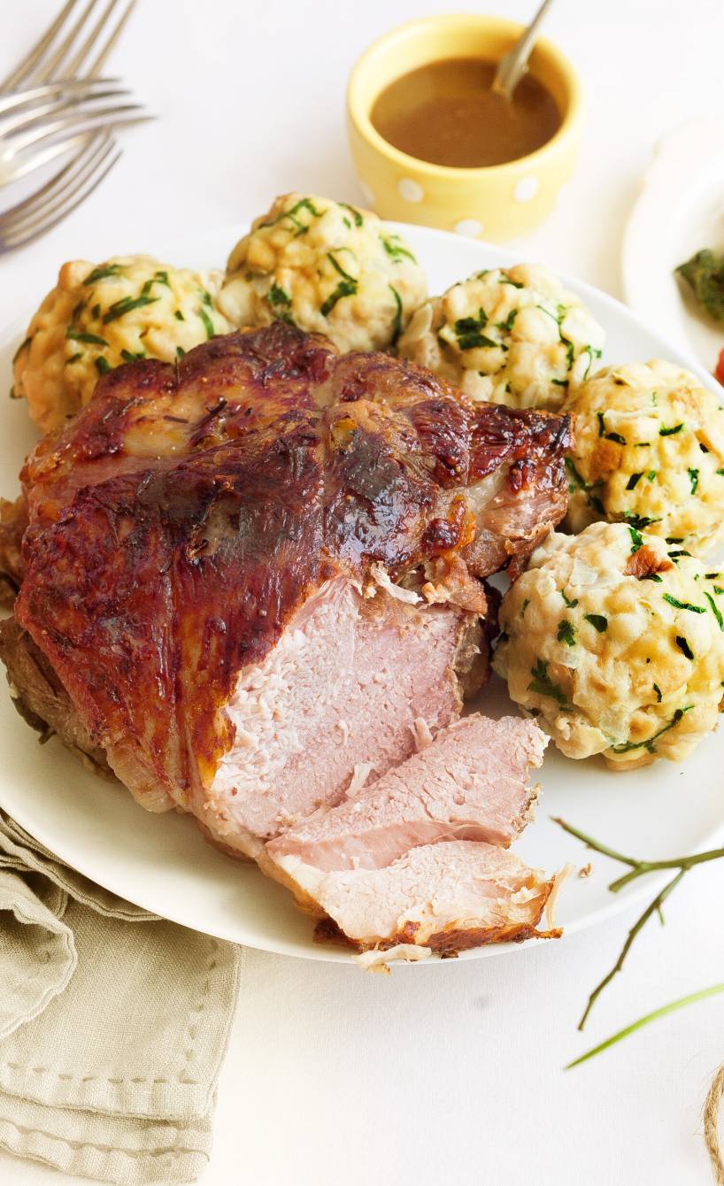 Angeschnittener Lammbraten mit Bärlauchknödeln auf einem Teller