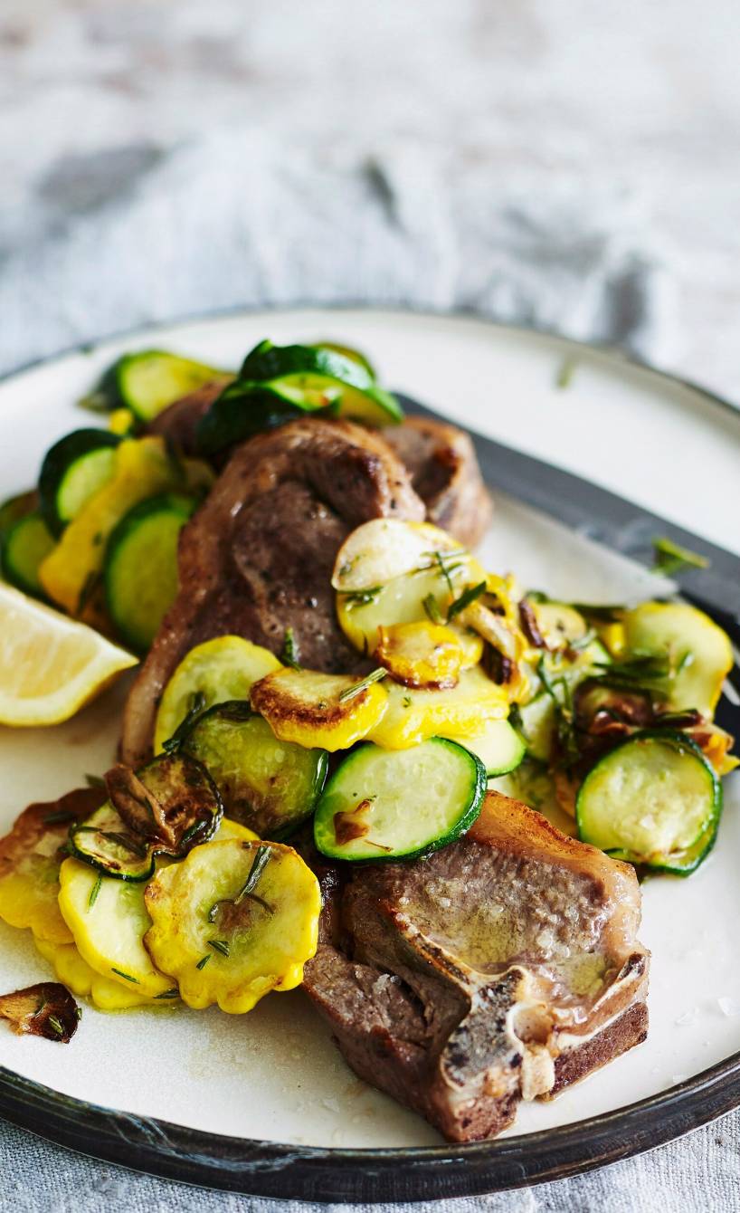 Lammkoteletts auf einem Teller getoppt vonKürbis-Zucchini-Gemüse