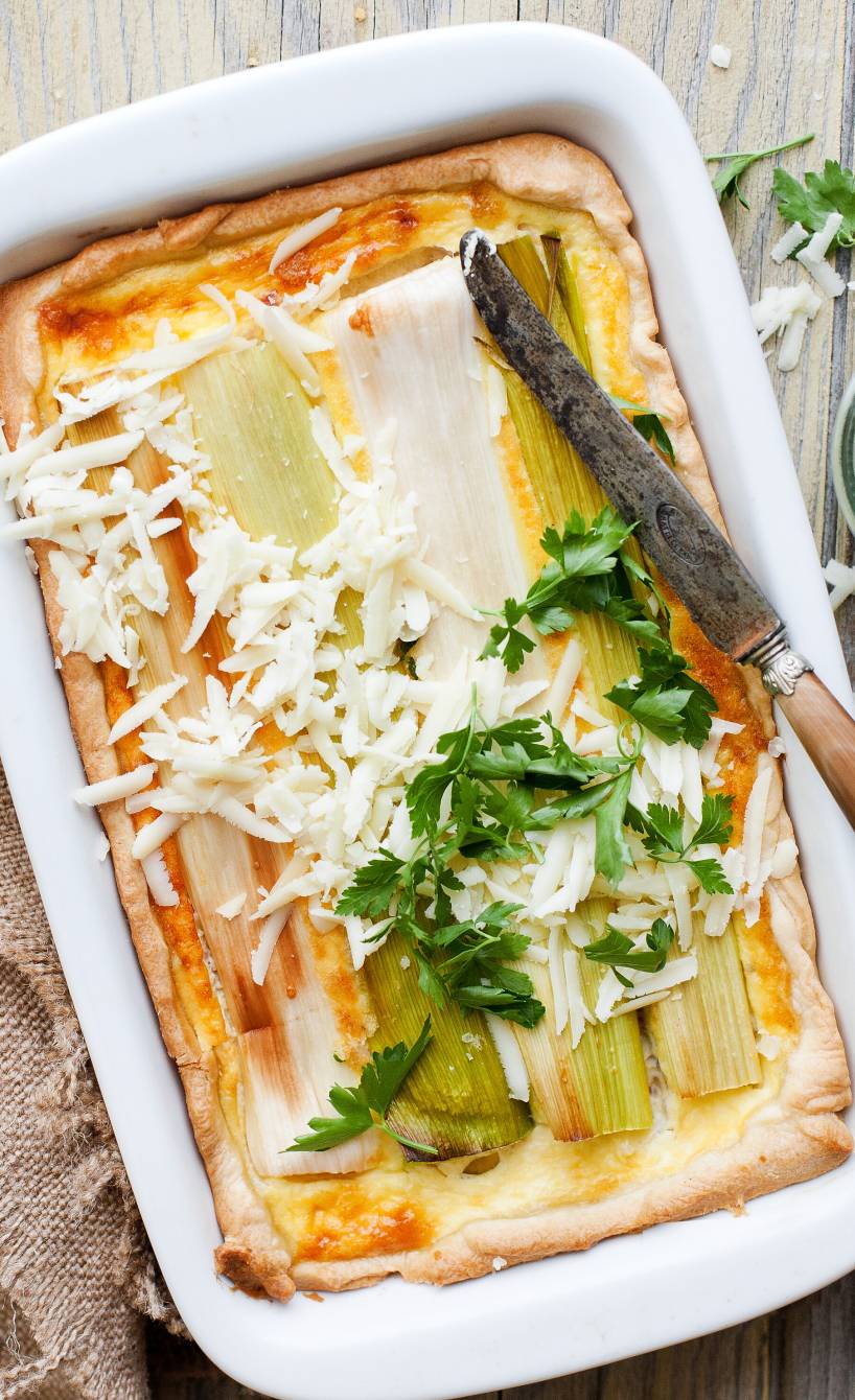 Blätterteig-Auflauf mit Schinken in einer Auflaufform belegt mit Lauchstangen und überbacken mit Käse