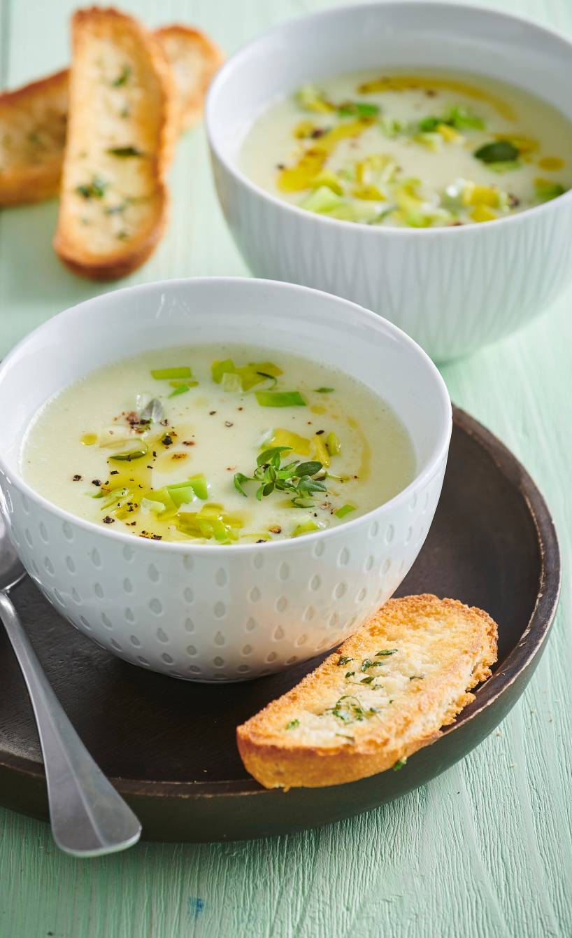 Lauchcremesuppe in zwei Suppentellern, daneben selbstgemachte Knoblauch-Crostini als Beilage