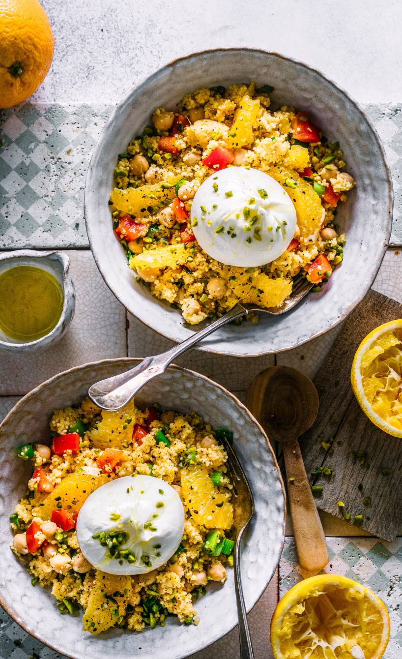 Zwei Schalen Couscoussalat mit Kichererbsen getoppt von Burrata und Pistazien