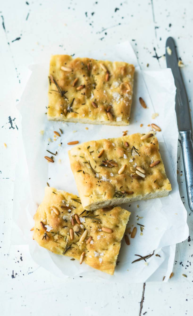 Drei Stücke selbstgebackener ligurischer Focaccia mit Pinienkernen auf einem Teller