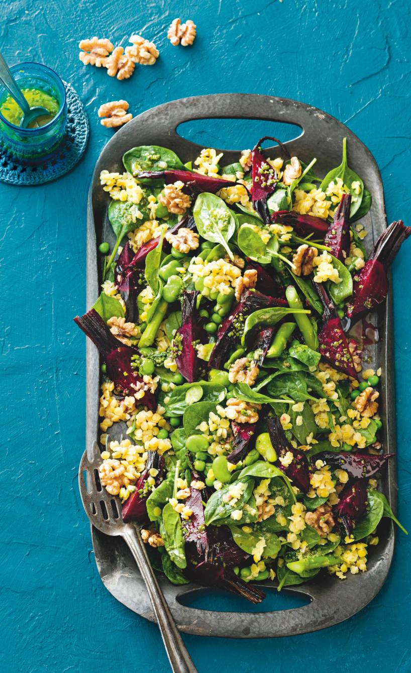 Veganer Linsensalat mit Rote Bete, Bohnen und Spinat auf einer Servierplatte getoppt von Walnüssen, daneben Ingwerdressing