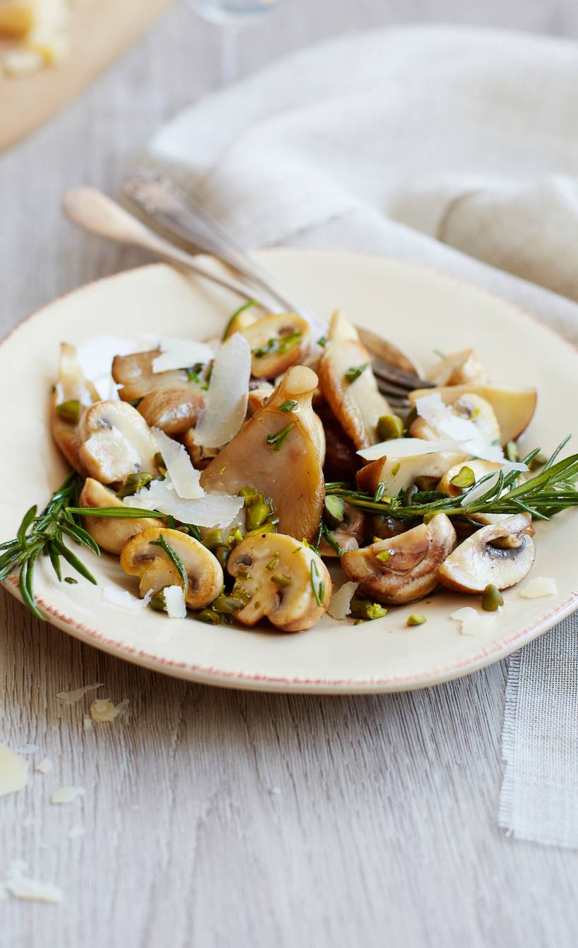 Marinierter Pilzsalat mit Pistazien und Parmesan getoppt von Rosmarinzweigen auf einem Vorspeisenteller