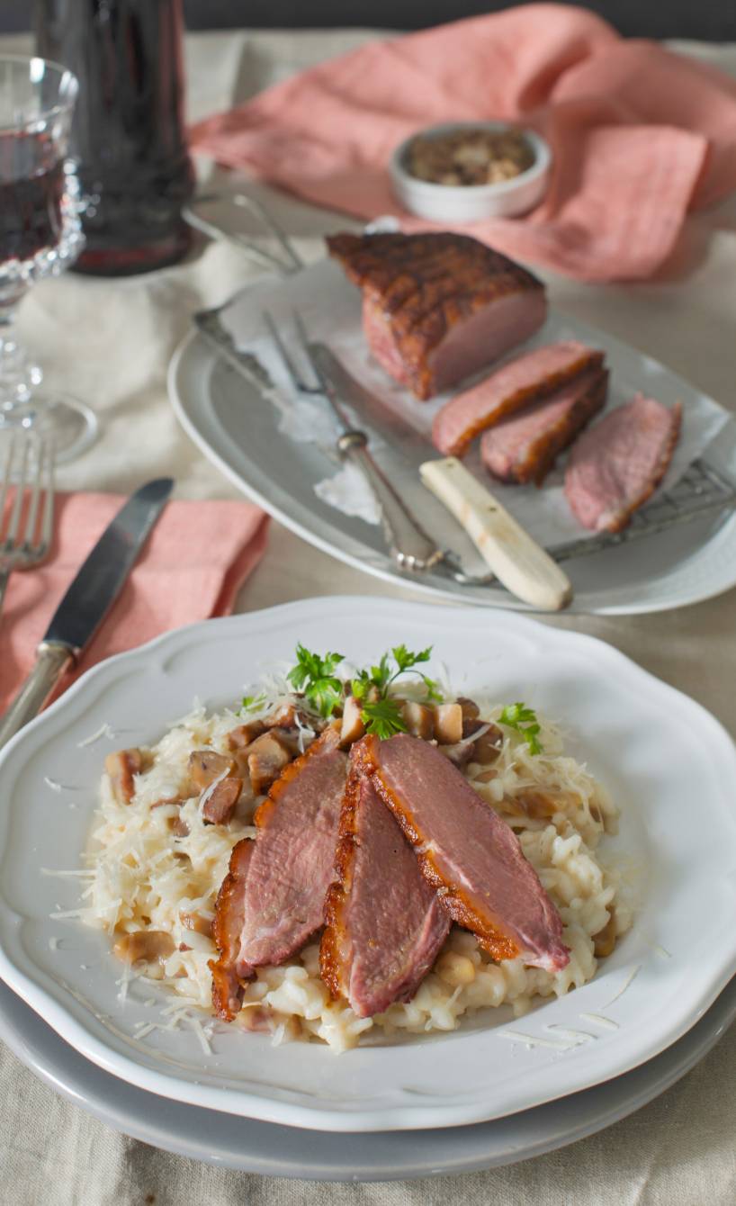 Entenbrust in Scheiben auf Risotto angerichtet auf einem weihnachtlich dekorierten Tisch