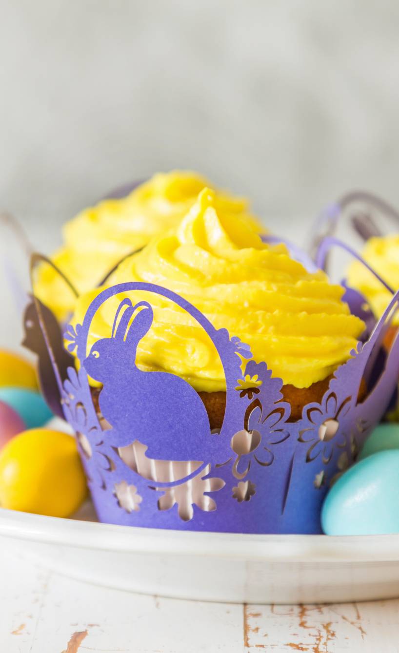 Eierlikörmuffins mit Buttercreme in österlichen Formen auf einem Teller mit Dropseiern