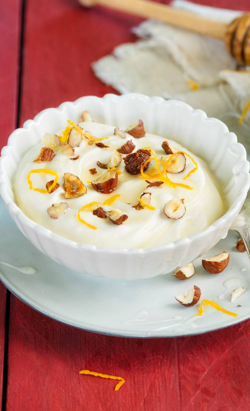 Mascarpone-Nachtisch in Glasschalen garniert mit Honig, Haselnüssen und Orangeszesten