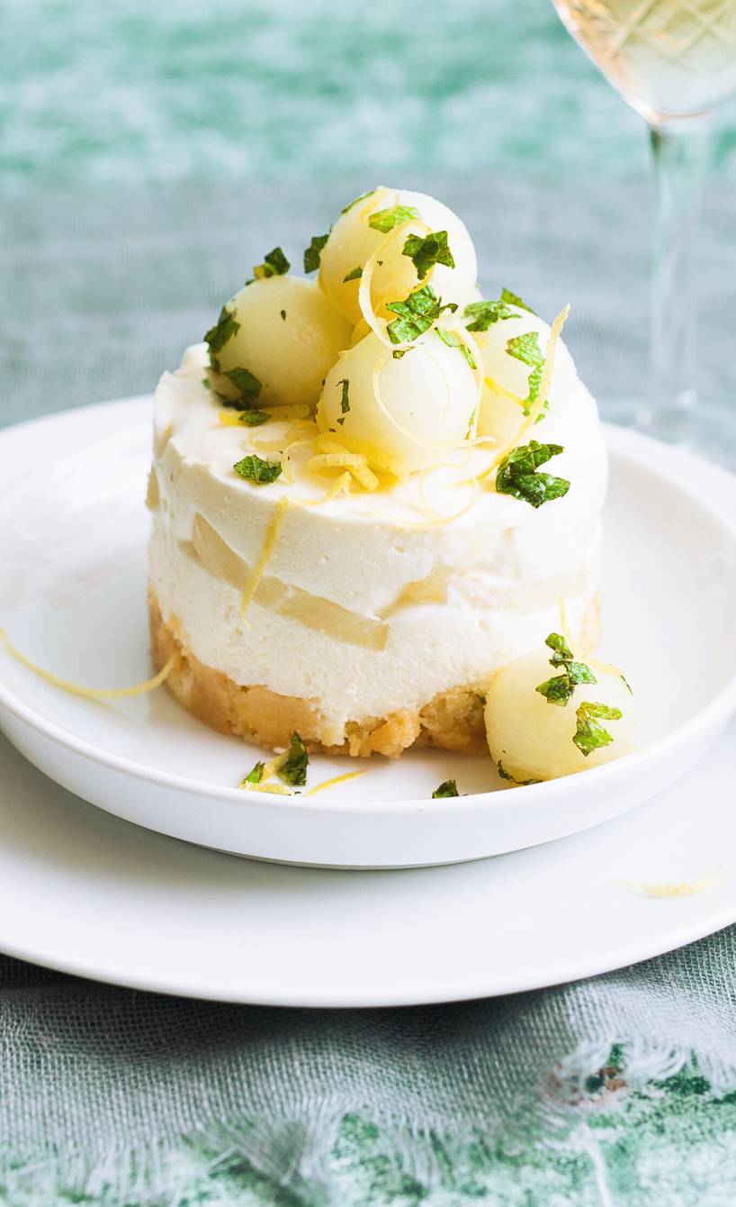 Törtchen aus Joghurt-Sahne-Creme und Melone auf einem Dessertteller dekoriert mit Minze