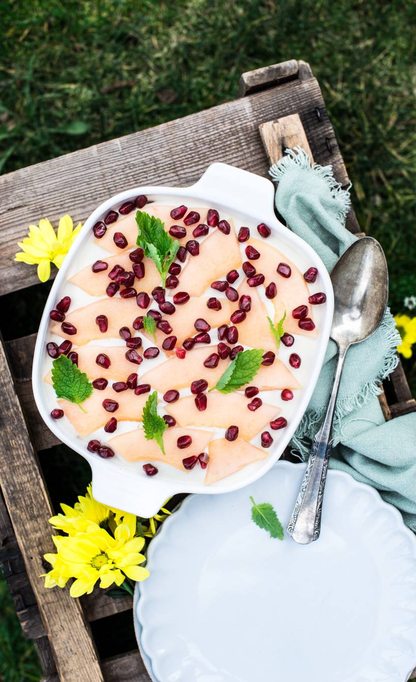 Tiramisu auf einem Gartnetisch getoppt mit Melonensplaten und Granatapfelkernen