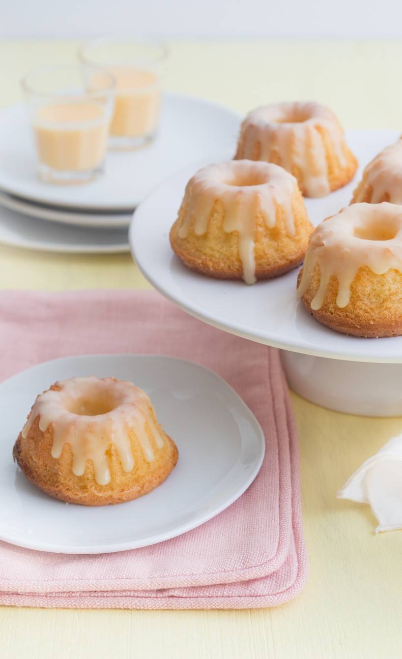 Mini-Gugelhupfe auf einer Tortenplatte, dahinter Shotgläser mit Eierlikör