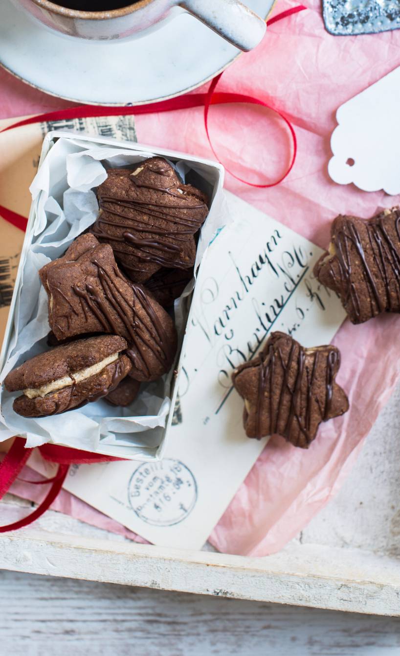 Sternförmige Mokkaplätzchen mit Füllung auf einem weihnachtlich dekorierten Kaffeetisch