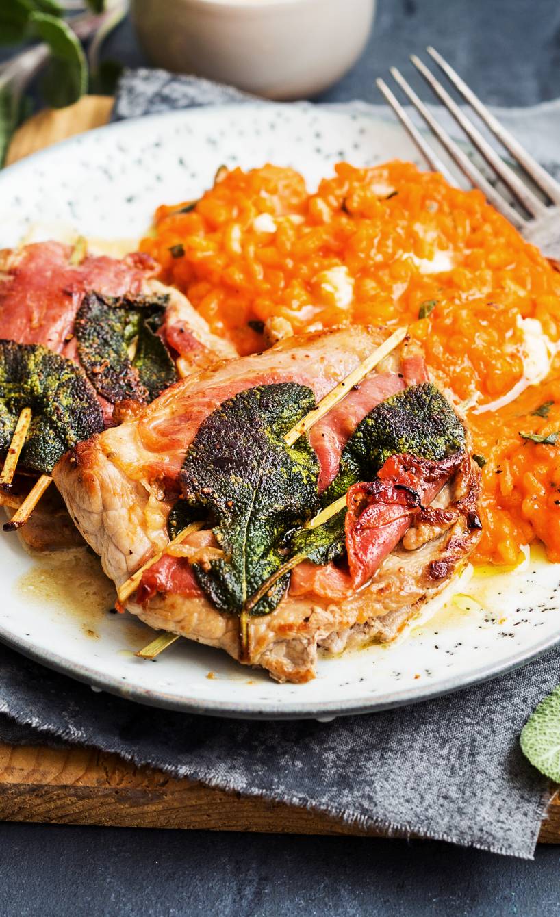 Saltimbocca alla romana auf einem Teller, daneben Risotto und Soße