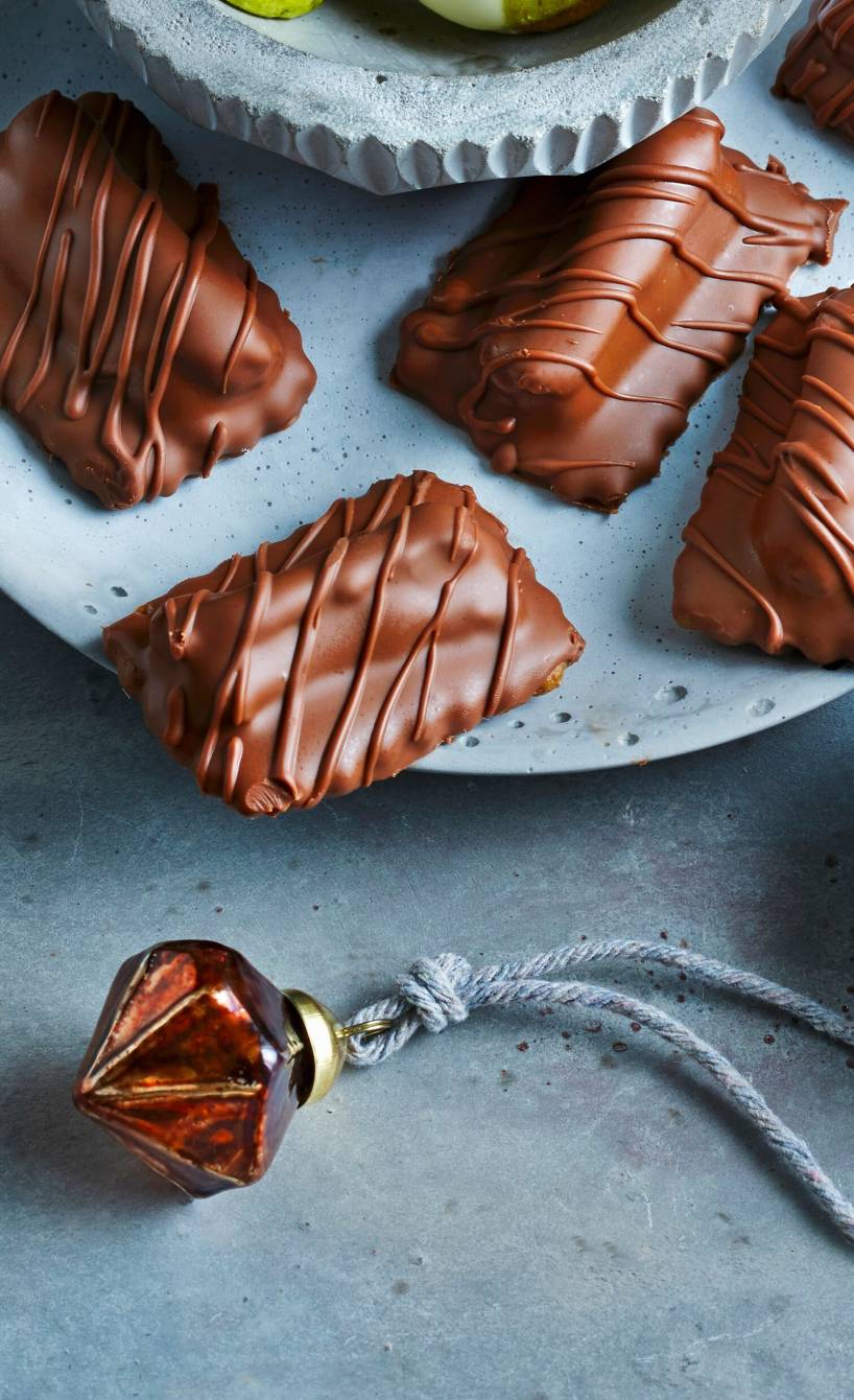 Selbst gemachte Nougat-Plätzchen mit Marzipan, Nüssen und Likör neben anderen Plätzchensorten auf einem Teller