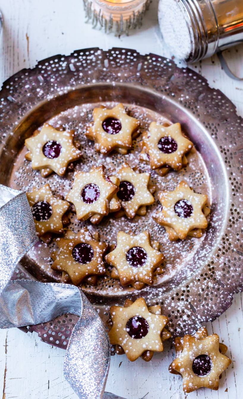 Haselnussplätzchen-Sterne mit Johannisbeerfüllung auf einem Plätzchenteller