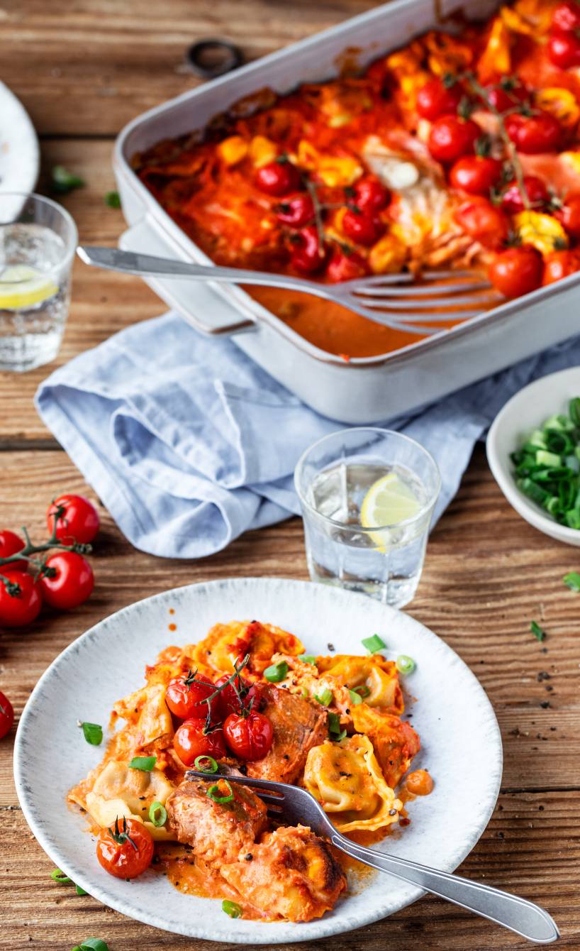 Ofenlachs und Tortellini in Tomaten-Sahne-Soße angerichtet auf einem Teller