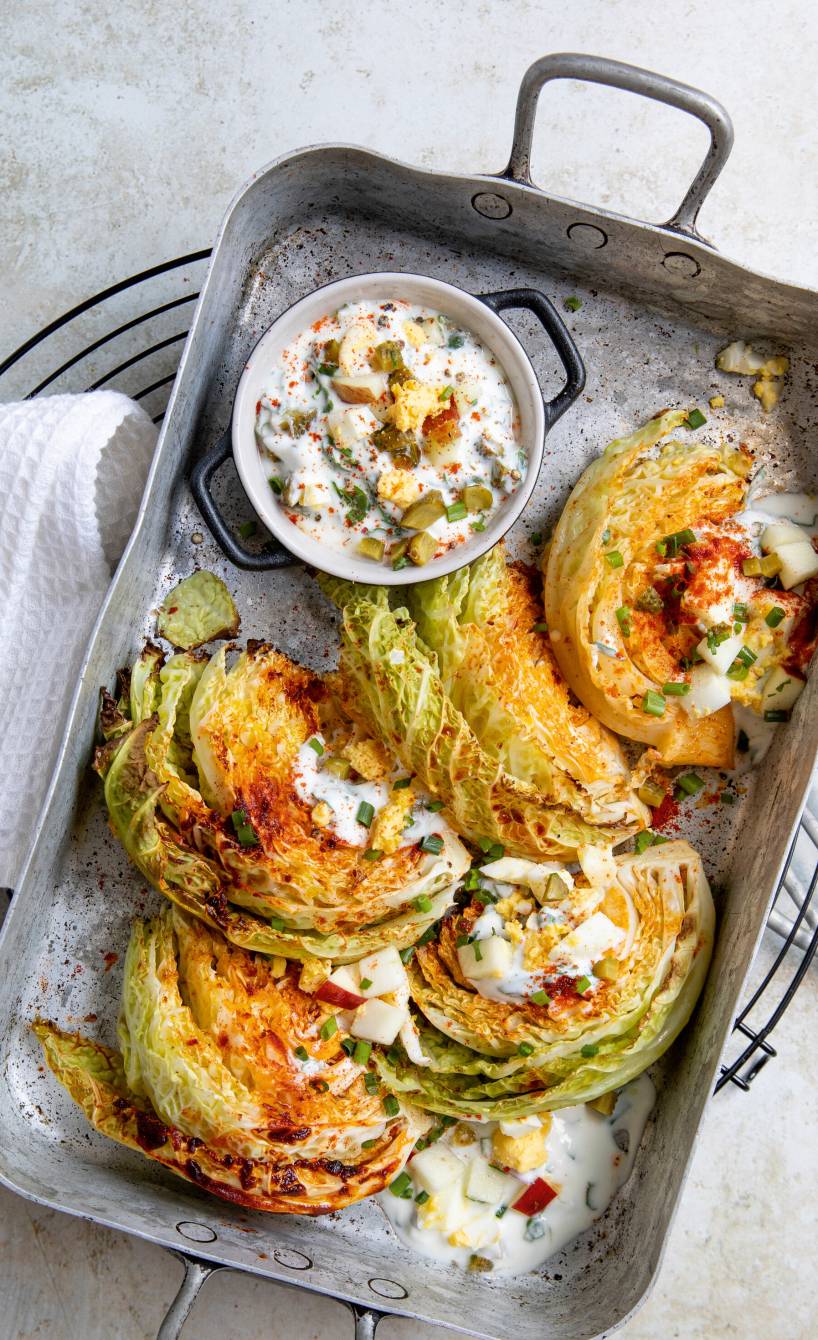 Gebackene Wirsingsplaten auf einem Backblech getoppt von gehackten Eiern und Kräuter-Joghurt-Creme