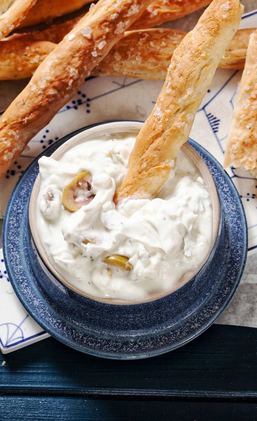 Olivendip mit Ziegenkäse und Joghurt in einer Schale, serviert mit Grissini