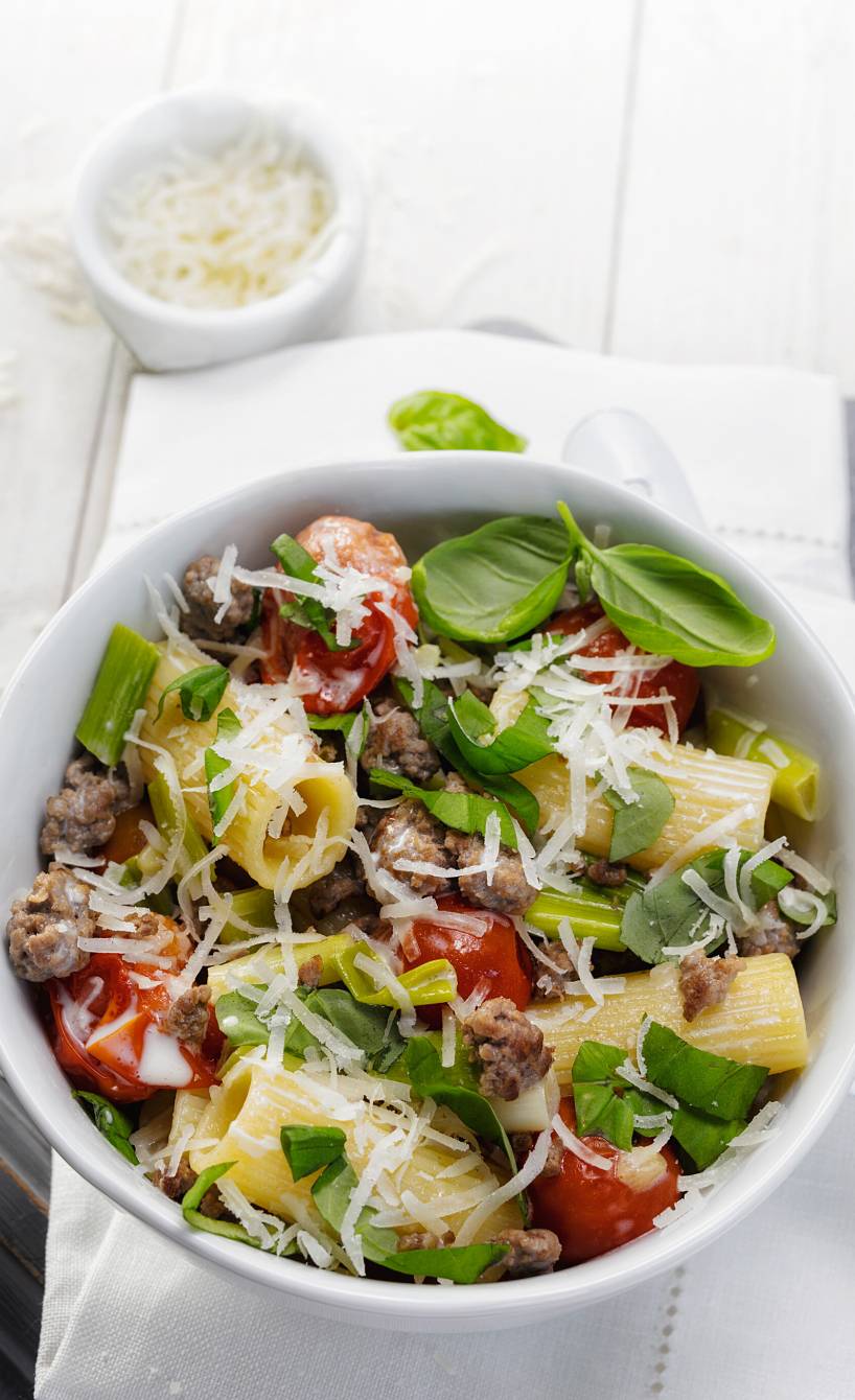 Topf mit One-Pot-Pasta mit Lammhackfleisch, Tomaten und Sahnesauce auf einem Tisch
