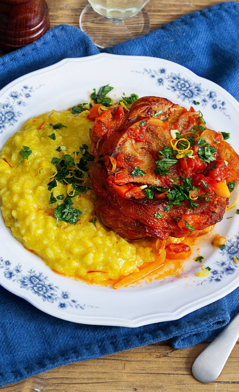 Kalbfleisch mit Sauce auf einem Teller, daneben Safranrisotto