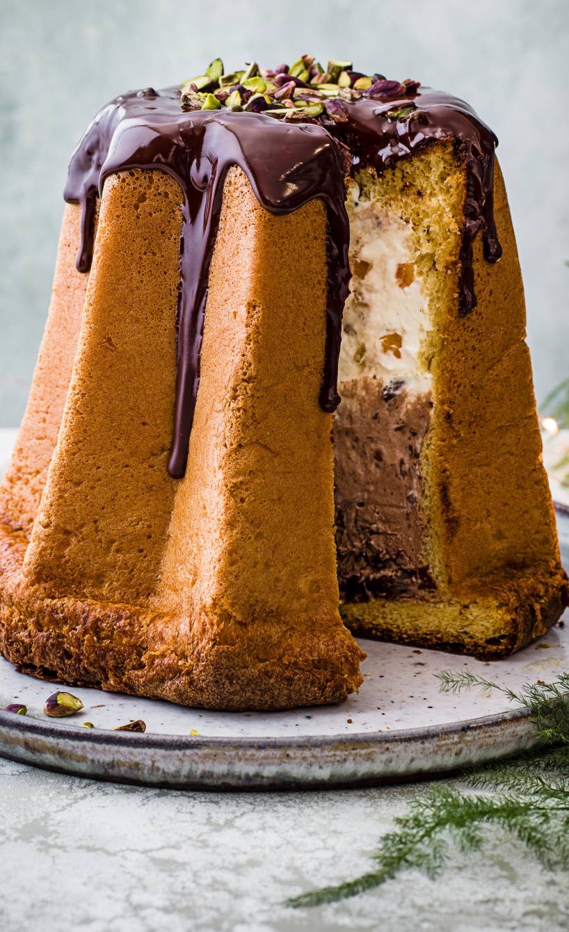 Pandoro Weihnachtskuchen angeschnitten auf einem runden Teller, dahinter Weihnachtsdeko