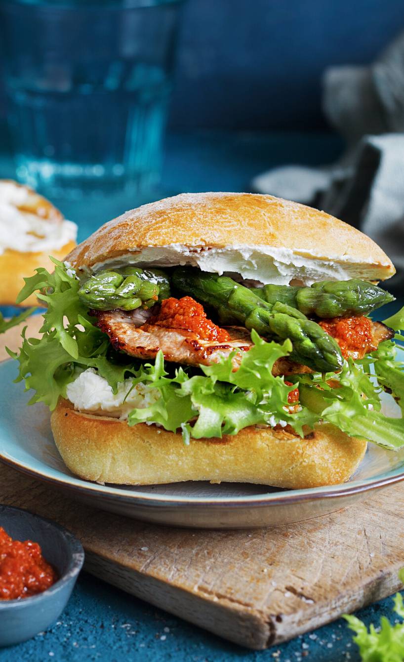 Belegtes Panini aus Ciabattabrötchen mit rotem Pesto, Spargel und Kalbsschnitzel auf einem Teller