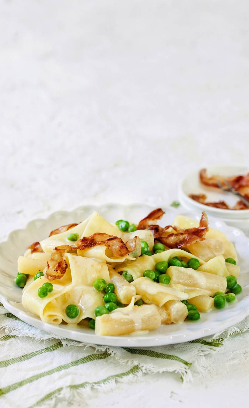 Pappardelle mit Schwarzwurzel-Rahm, Erbsen und krossem Pancetta angerichtet auf einem Teller