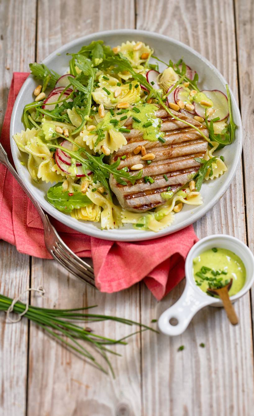 Pastasalat und Thunfischsteak vom Grill auf einem Teller, daneben Pesto