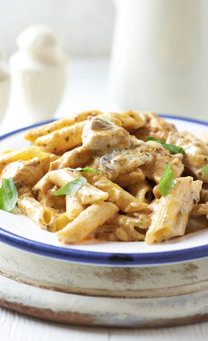 Penne Käsesoße und Putenschnitzelstreifen auf einem Teller