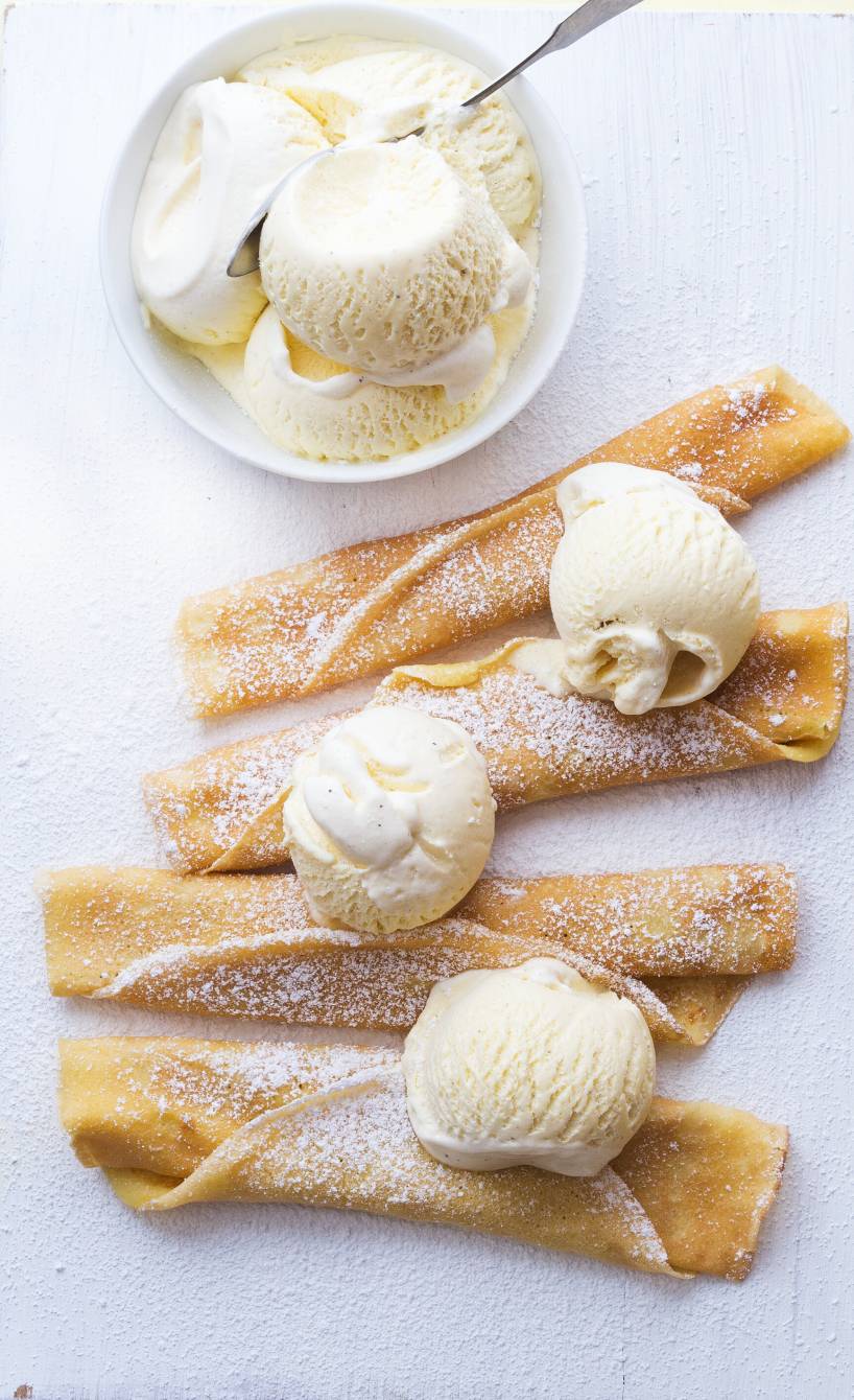 Pfannkuchen aufgerollt nebeneinander auf einem Teller getoppt von Vanilleeis