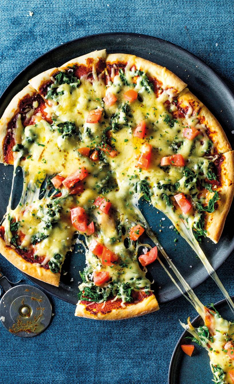 Vegetarische Mangold-Pizza angeschnitten auf einem Pizzateller