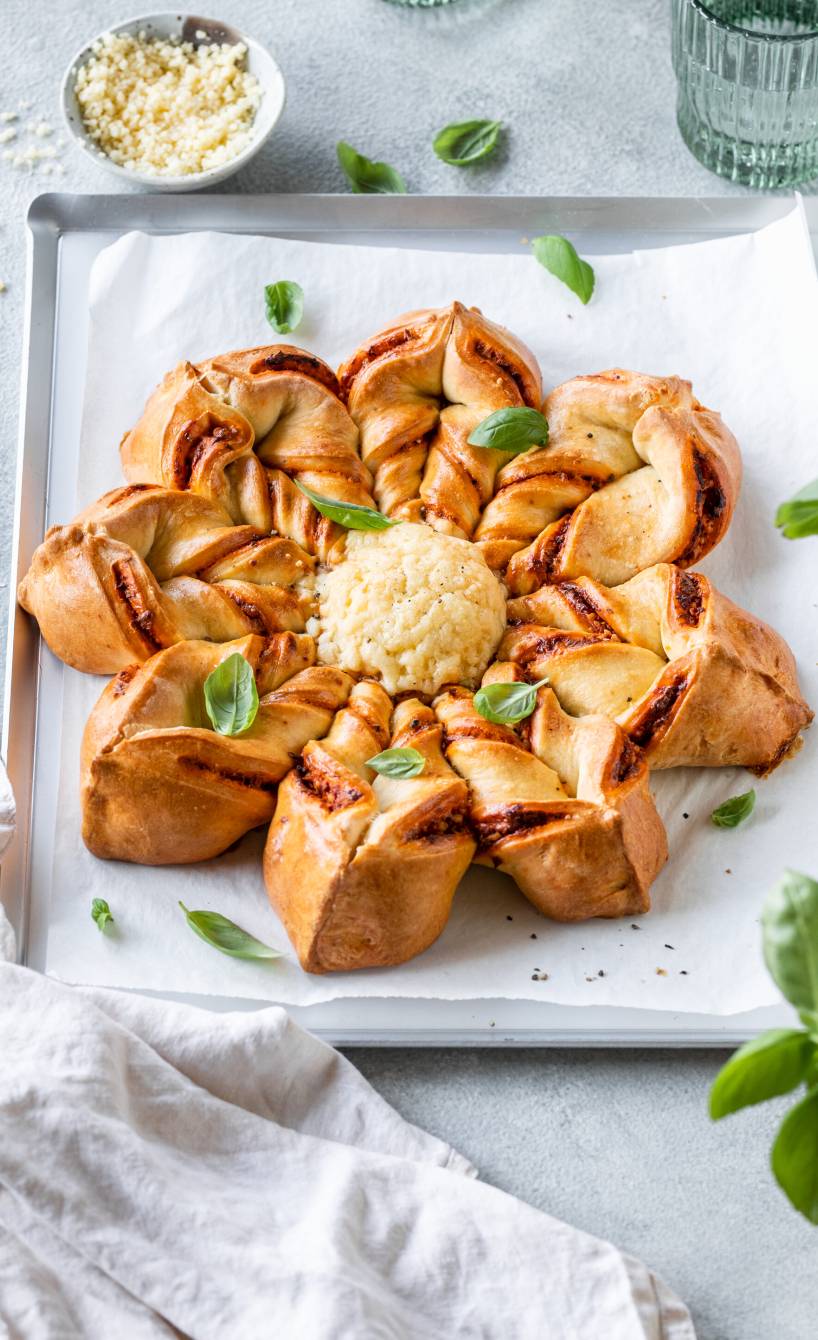 Selbstgebackene Pizzablume mit geschmolzenem Mozzarella in der Mitte auf einer Servierplatte