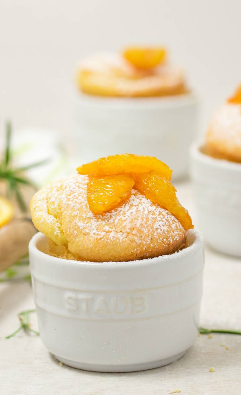 Drei süße Polentaküchlein in Mini-Backformen getoppt mit Rosmarin und Orangenkompott auf einem Tisch