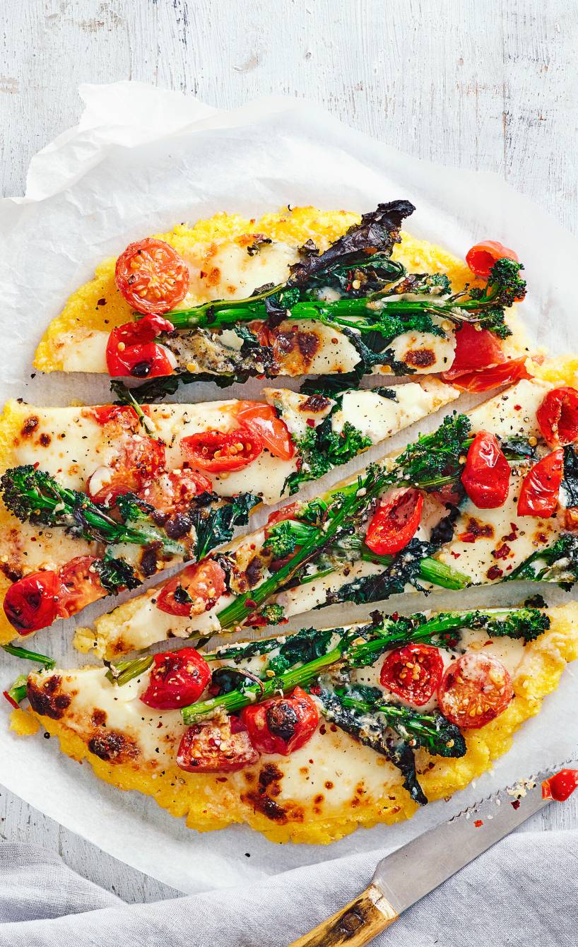 Runde Polentapizza mit Gemüse und Mozzarella in Streifen geschnitten auf einem Teller