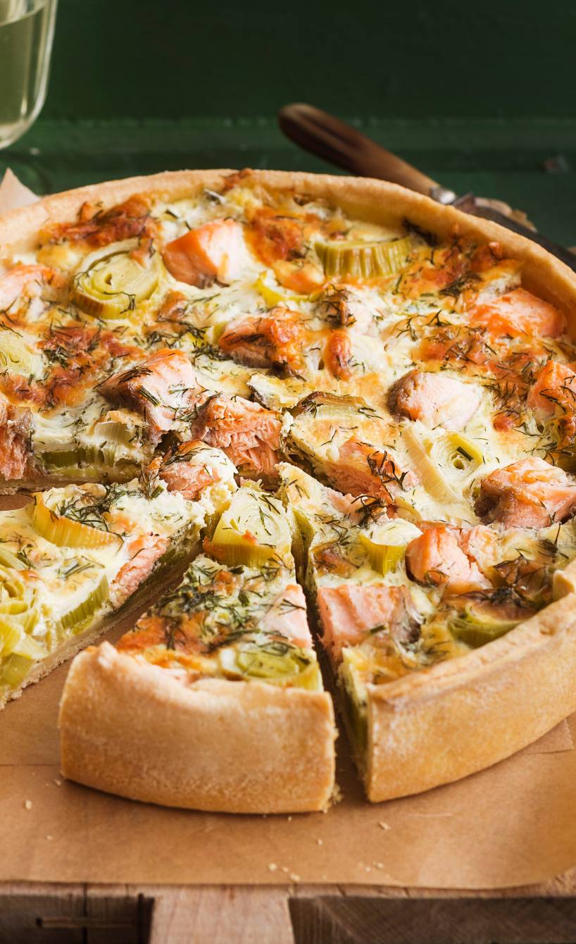 Lachs-Quiche angeschnitten auf einem Holzbrett
