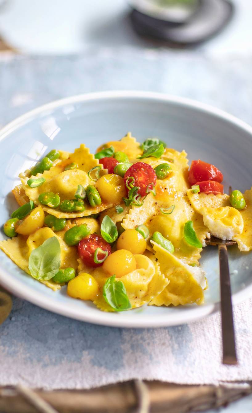 Selbst gemachte Ravioli auf einem Teller getoppt von Tomaten und Favabohnen