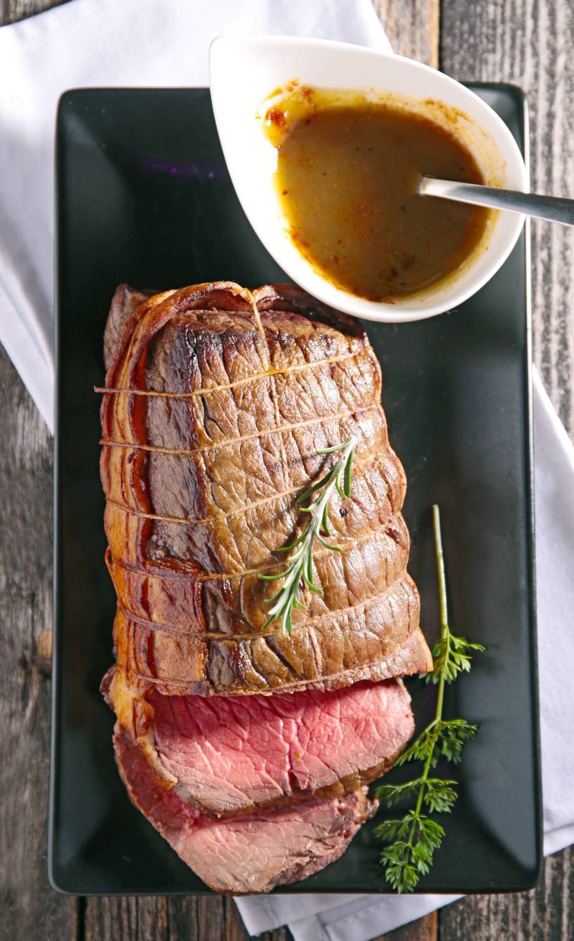 Ganzer Rinderbraten angeschnitten, daneben Portweinsoße in einer Sauciere