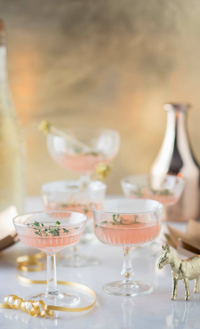 Rosa Weihnachtspunsch in mehrere Sektschalen auf einem festlich dekorierten Tisch