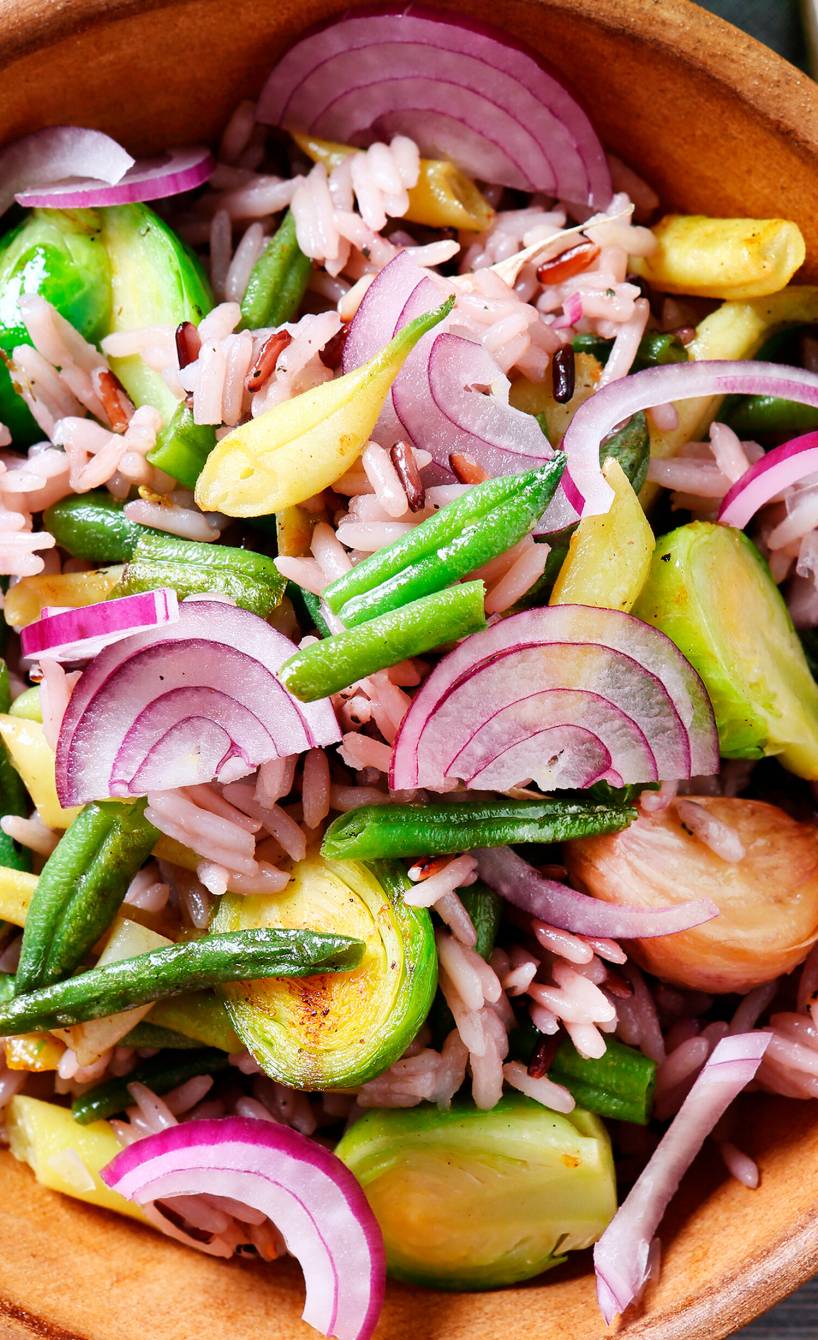 Rosenkohlsalat mit Reis & Bohnen in einer Salatschüssel, daneben Essig-Öl-Dressing