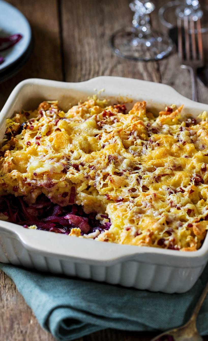 Rotkohl-Spätzle-Auflauf in einer Auflaufform auf einem Holztisch überbacken mit Käse
