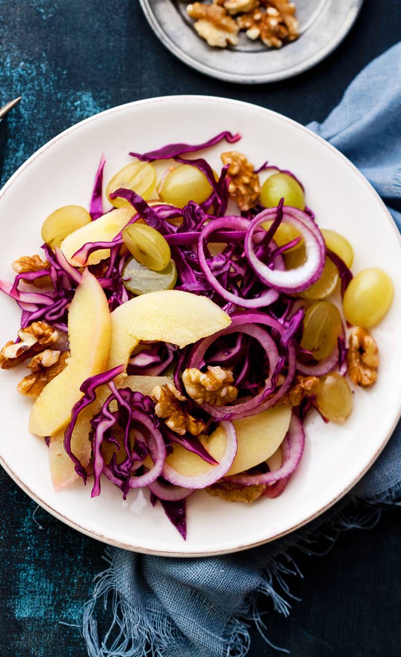 Rotkohlsalat mit Quitten, Trauben und Walnüssen angerichtet auf einem Teller