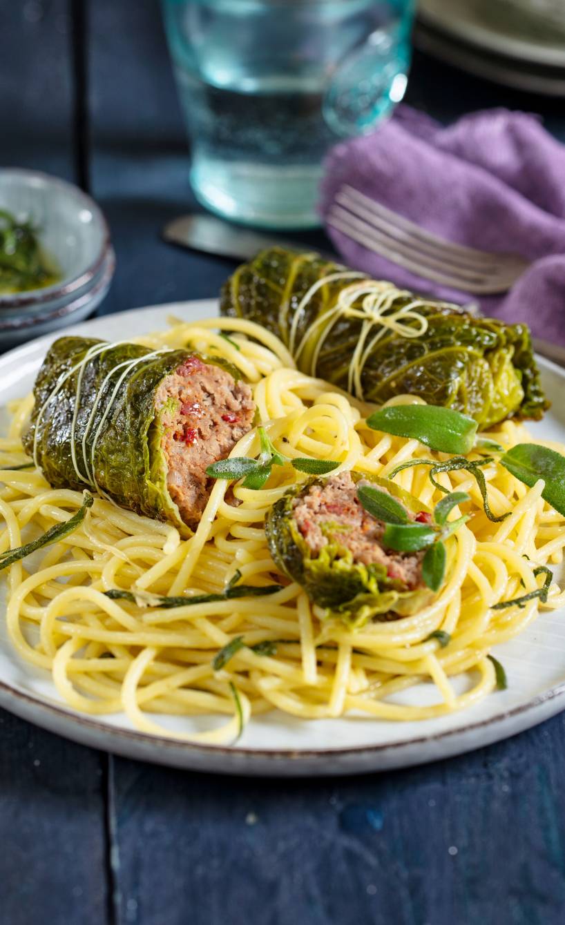 Wirsingrouladen auf Salbeispagehetti angerichtet auf einem Teller