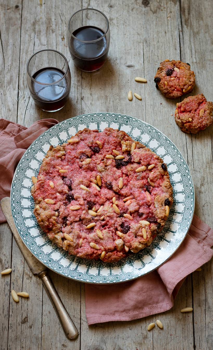 Rosa Kuchen auf einem Kuchenteller getoppt von Pinienkernen