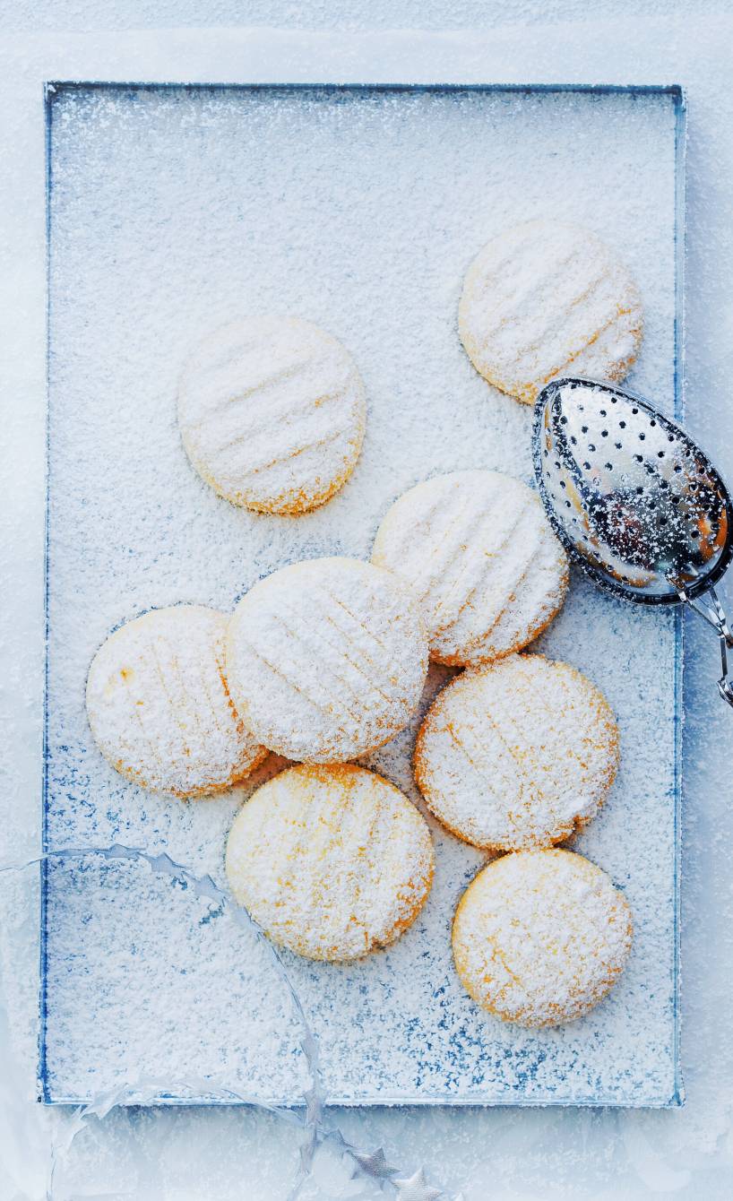 Schneeflöckchen-Plätzchen auf einem rechteckigen Teller, daneben Weihnachtsdeko