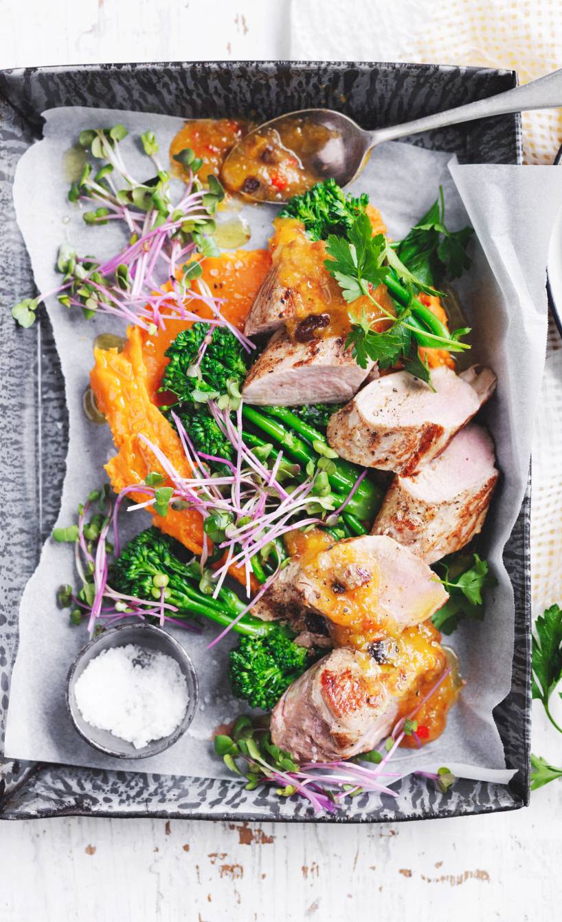 Schweinebraten auf einer Servierplatte getoppt mit Salsa und Brokkolini, daneben Süßkartoffelstampf
