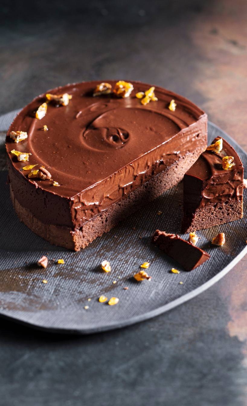 Schokomousse-Torte angeschnitten auf einer Tortenplatte garniert mit Pekannuss-Krokant