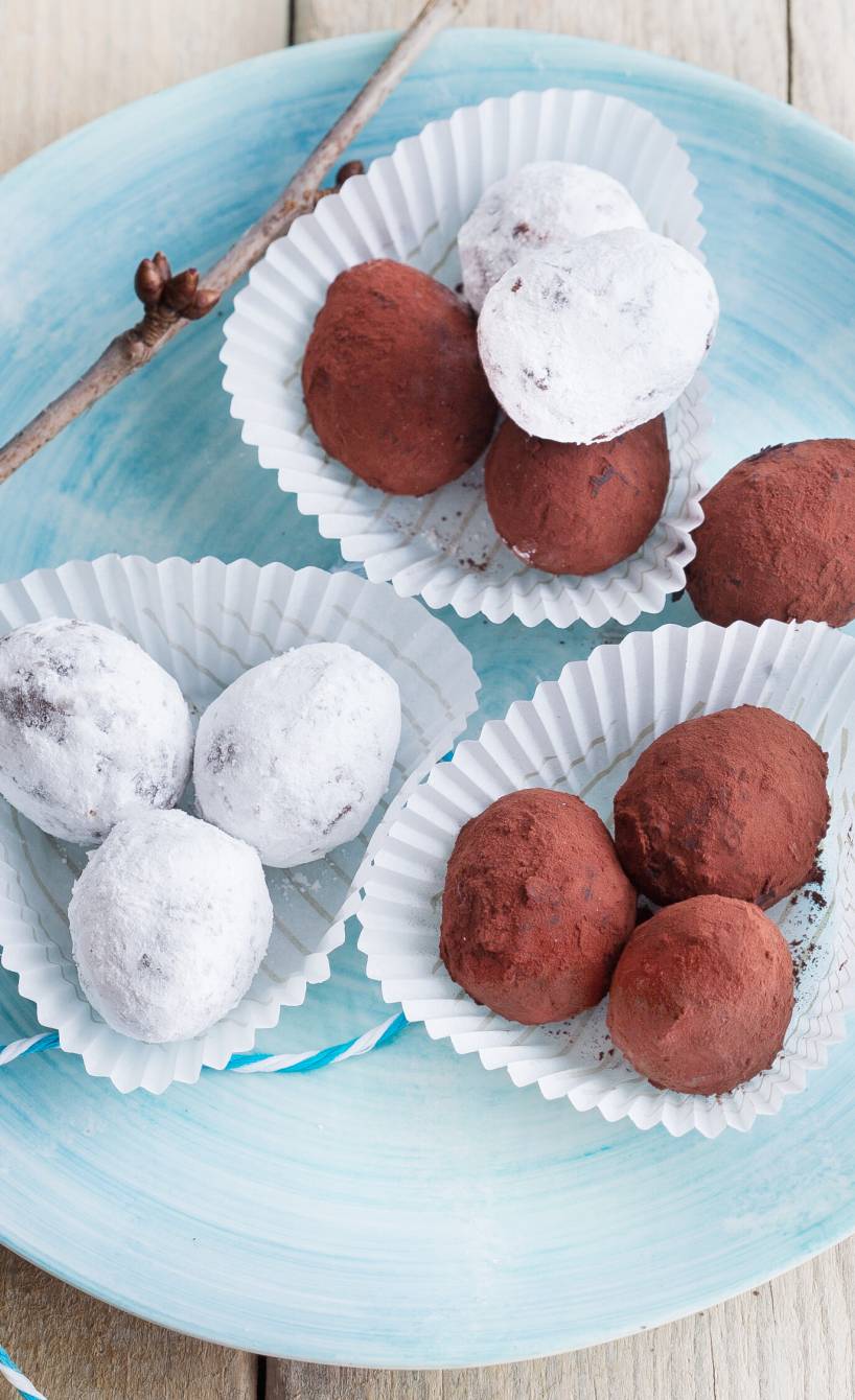 Selbstgemachte Kaffee-Schokotrüffel mit zweierlei Ummantelung angerichtet in Pralinenförmchen auf einem Dessertteller