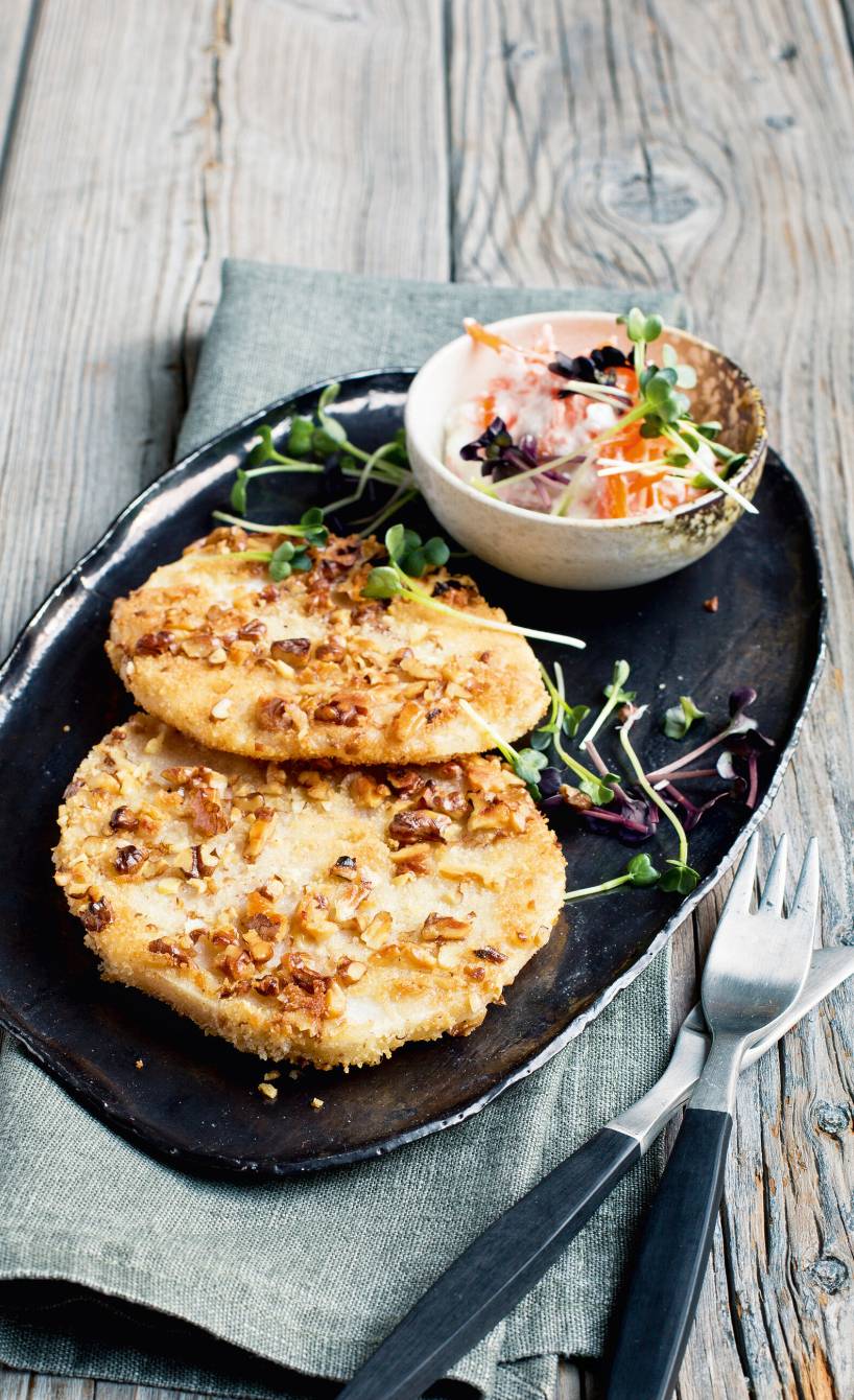 Sellerieschnitzel in Walnusspanade auf einem Teller, daneben Dip