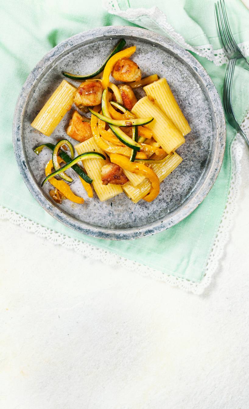 Pastasalat aus Rigatoni auf einem Teller mit gebratenem Hähnchen, Zucchini und Paprika