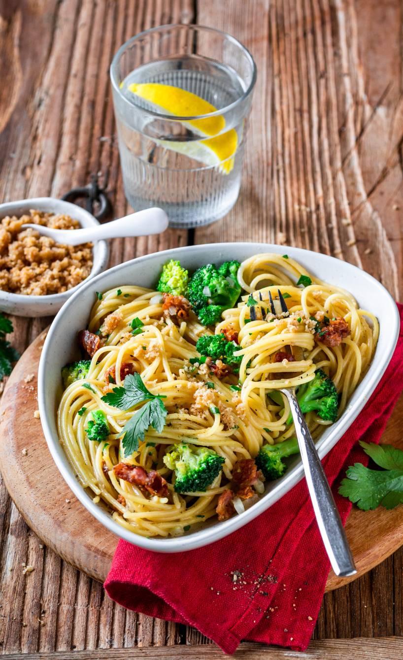 Spaghetti mit Brokkoli-Carbonara in einem ovalen, tiefen Teller auf einem Tisch